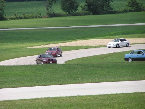 1993 Ford Taurus - Several cars are seen on a race track during a sunny day.