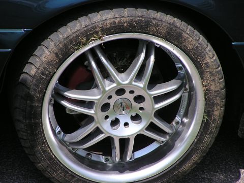 1993 Ford Taurus - Aftermarket wheel and tire with visible 'Momo' branding, showing wear and debris.