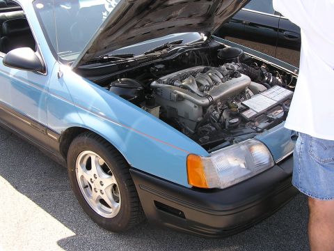 1993 Ford Taurus - The engine bay of a 1993 Ford Taurus is visible with the hood raised, its mechanical components.