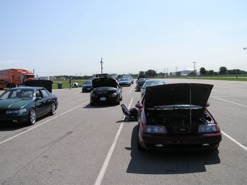1993 Ford Taurus - Cars are parked in an outdoor lot with their hoods open under a clear sky.