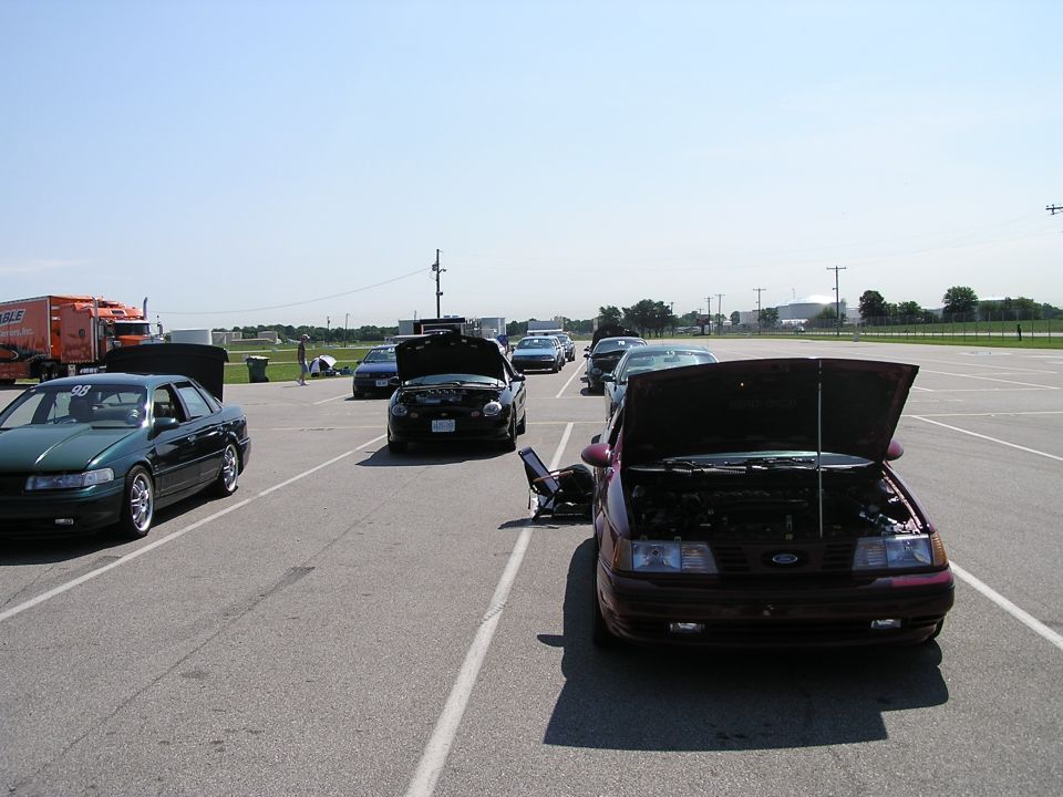 several cars with hoods up parked in a lot