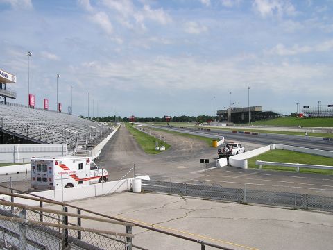 1993 Ford Taurus - An ambulance and a pickup truck are parked near the start line of a drag strip, with empty grandstands in the background.
