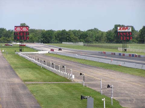 1993 Ford Taurus - Two cars compete on a drag strip, with large digital timers displaying their race times.