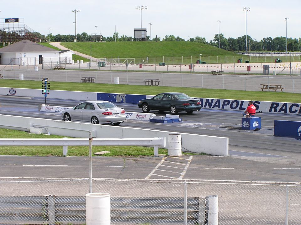 Dark green sedan on drag strip, side view