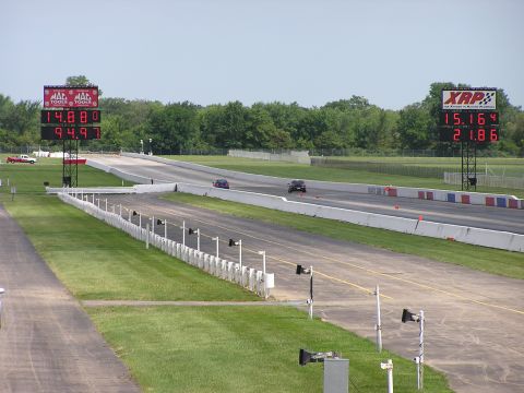 1993 Ford Taurus - Two cars compete on a drag strip, with large digital scoreboards displaying their race times.