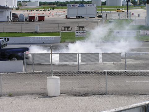 1993 Ford Taurus - Pickup truck performing a burnout on a drag strip, with a yellow car visible in the distance.