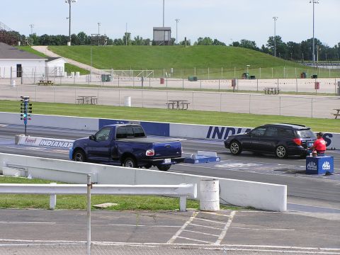 1993 Ford Taurus - Two vehicles are staged at the starting line of a drag strip, with a Christmas tree light system visible.