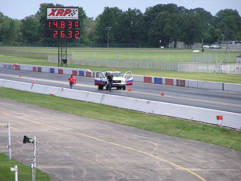 1993 Ford Taurus - A tow truck is stopped on the drag strip with its doors open, under a large XRP scoreboard displaying times.