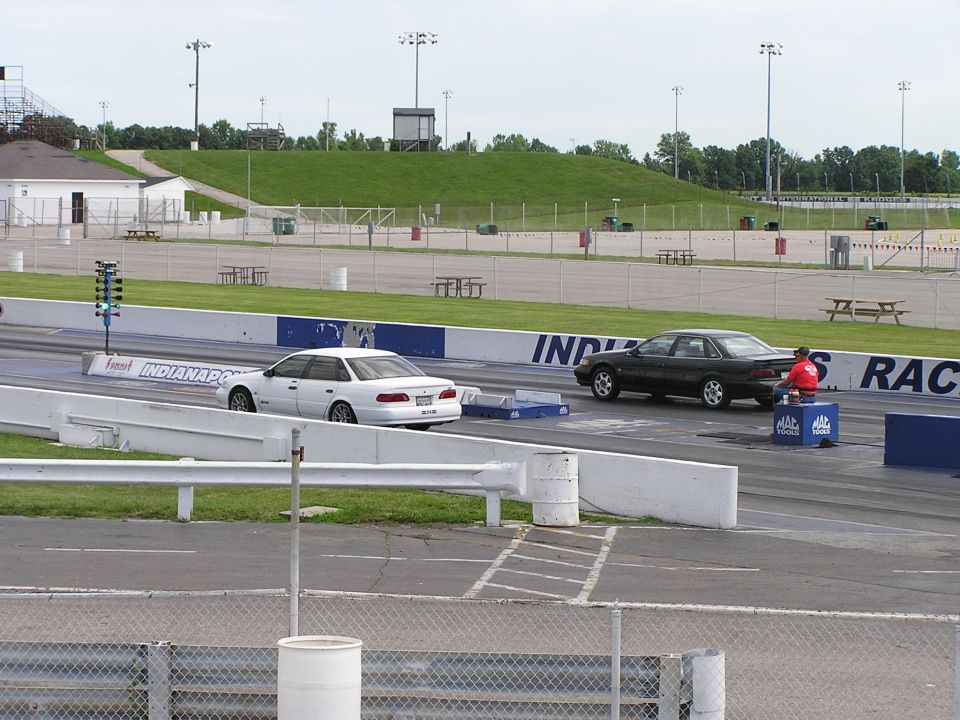 1993 Ford Taurus and a dark sedan staged on a drag strip with a Christmas tree light system
