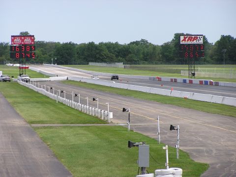 1993 Ford Taurus - A drag race is underway with two vehicles competing on the track, as indicated by the large digital scoreboards.