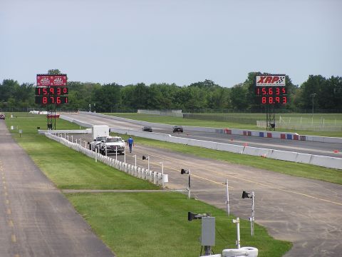 1993 Ford Taurus - Two cars compete on a drag strip, with digital scoreboards displaying their race times.