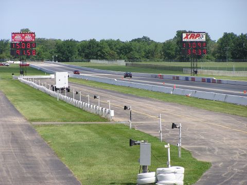 1993 Ford Taurus - Two cars compete on a drag strip, with large digital timers displaying their race times.