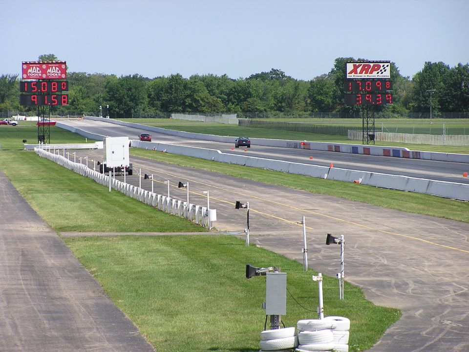 Drag strip with two cars racing, digital timers showing times
