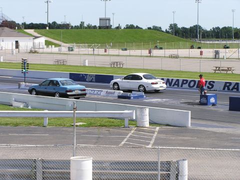 1993 Ford Taurus - A white sedan, likely a 1995 Ford Taurus, races down a drag strip alongside a blue sedan.