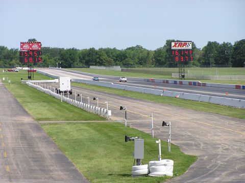 1993 Ford Taurus - Two cars compete on a drag strip under scoreboards displaying race times.