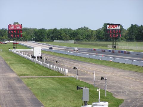 1993 Ford Taurus - Two cars compete on a drag strip, with large digital timers displaying their race times.