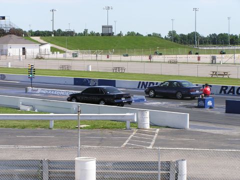 1993 Ford Taurus - Two sedans, including a black 1993 Ford Taurus, line up at the start of a drag race.