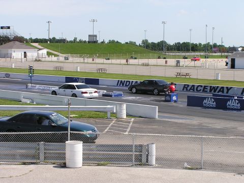 1993 Ford Taurus - Cars line up at the starting line of a drag strip on a sunny day.