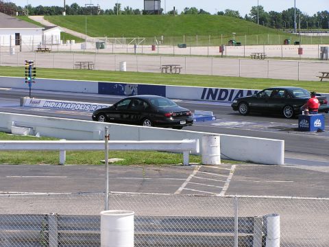 1993 Ford Taurus - Two black sedans race on a drag strip at Indianapolis Raceway.