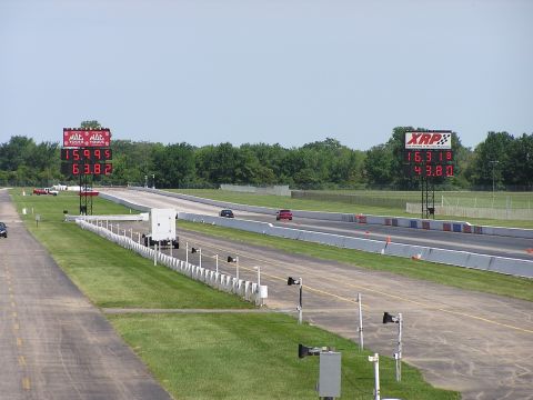 1993 Ford Taurus - A drag racing event is underway with cars on the track and digital timers displaying race results.