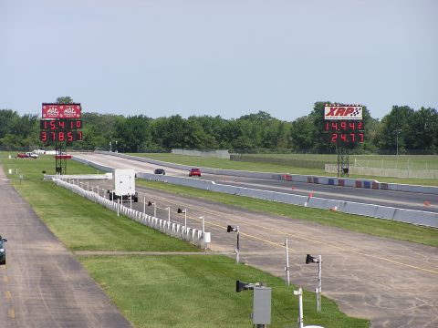 1993 Ford Taurus - Two cars compete on a drag strip, with large digital scoreboards displaying their race times.