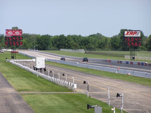 1993 Ford Taurus - Two cars compete on a drag strip, with large digital timers displaying their performance metrics.