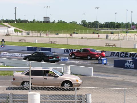 1993 Ford Taurus - Three sedans are lined up on a racetrack, with a tan 1993 Ford Taurus in the foreground.