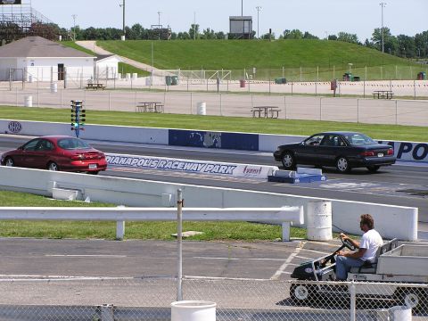 1993 Ford Taurus - A dark 1993 Ford Taurus sedan is seen from the rear on a drag strip, with another car visible ahead.