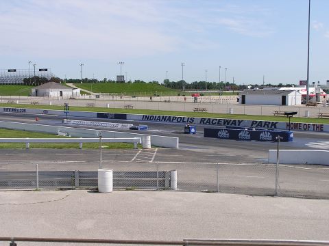 1993 Ford Taurus - The drag strip at Indianapolis Raceway Park is shown on a clear day with spectators' seating and support buildings visible.