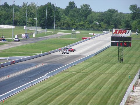 1993 Ford Taurus - A drag strip scene features two cars lined up, with a large scoreboard displaying a time of 14.91.