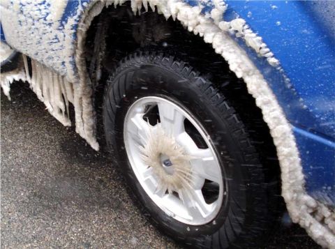 2008 Ford Crown Victoria - A blue vehicle's wheel well is heavily encrusted with ice and icicles, obscuring details of the vehicle itself.