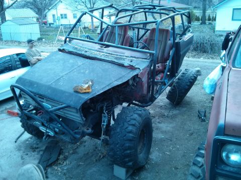 1986 Ford Bronco - Custom off-road buggy with extensive roll cage and large tires, parked next to another vehicle.
