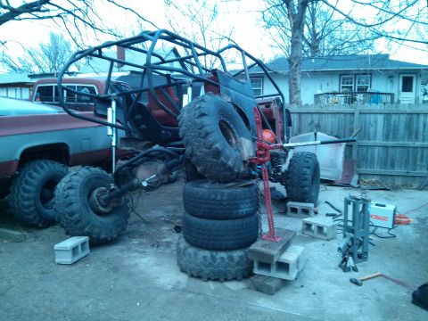 1986 Ford Bronco - A custom-built off-road buggy is shown in a backyard setting, supported by tires and a jack.