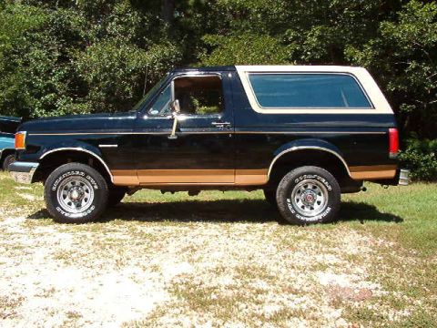1989 Ford Bronco - This Ford Bronco is parked on a grassy area with trees in the background.
