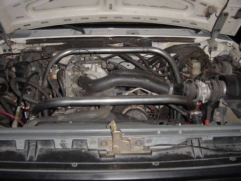 1987 Ford Bronco - Engine bay of a 1987 Ford Bronco, showing the engine and an installed roll cage.