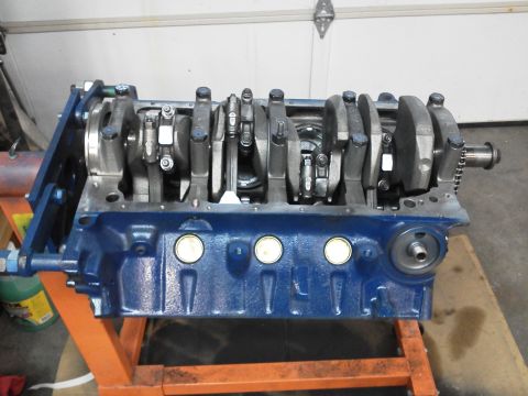 1988 Ford Bronco - A blue engine block assembly, the crankshaft and connecting rods, is mounted on an orange engine stand.