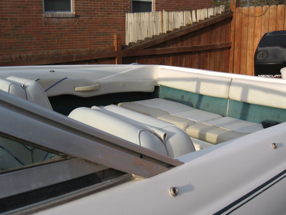 Interior of a white boat with green and white seats. A black Mercury outboard motor is visible in the background