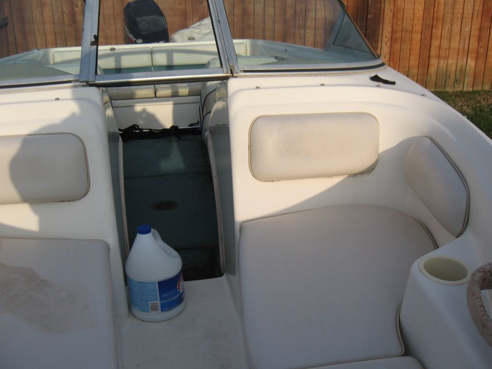 boat interior with white seats, a bottle of bleach, and an outboard motor visible