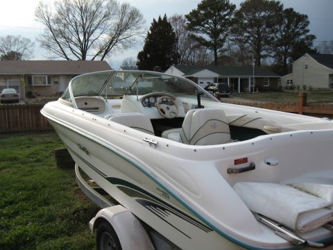 1994 Ford Bronco - White speed boat on trailer parked in front of suburban houses.