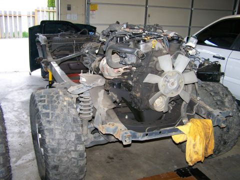 1988 Suzuki Samurai - This vehicle's chassis and engine are visible, with large off-road tires and a yellow rag attached to the frame.