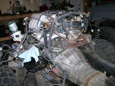 1988 Suzuki Samurai - Engine and transmission assembly in a garage setting, with a blue shop towel placed on top.