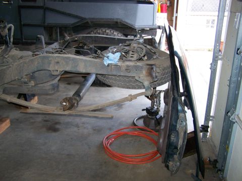 1988 Suzuki Samurai - The vehicle is disassembled in a garage, with parts laid out and the chassis elevated on stands.