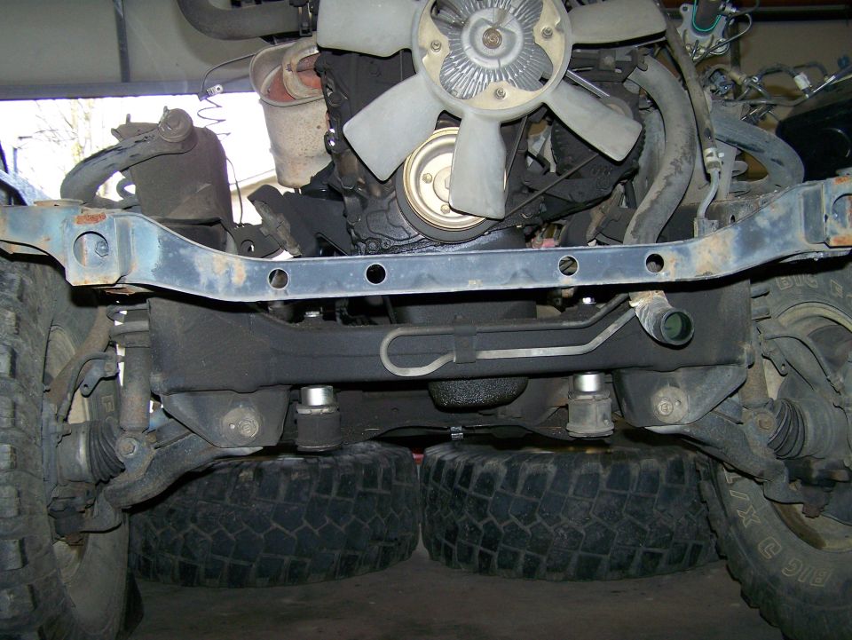 Underside view of a vehicle's engine and chassis with large tires visible