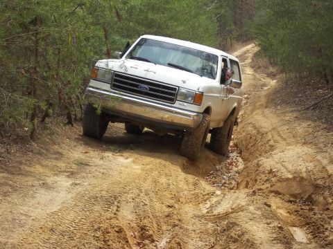 1990 Ford Bronco - This 1990 Ford Bronco tackles a challenging off-road path, demonstrating its capability on rough terrain.
