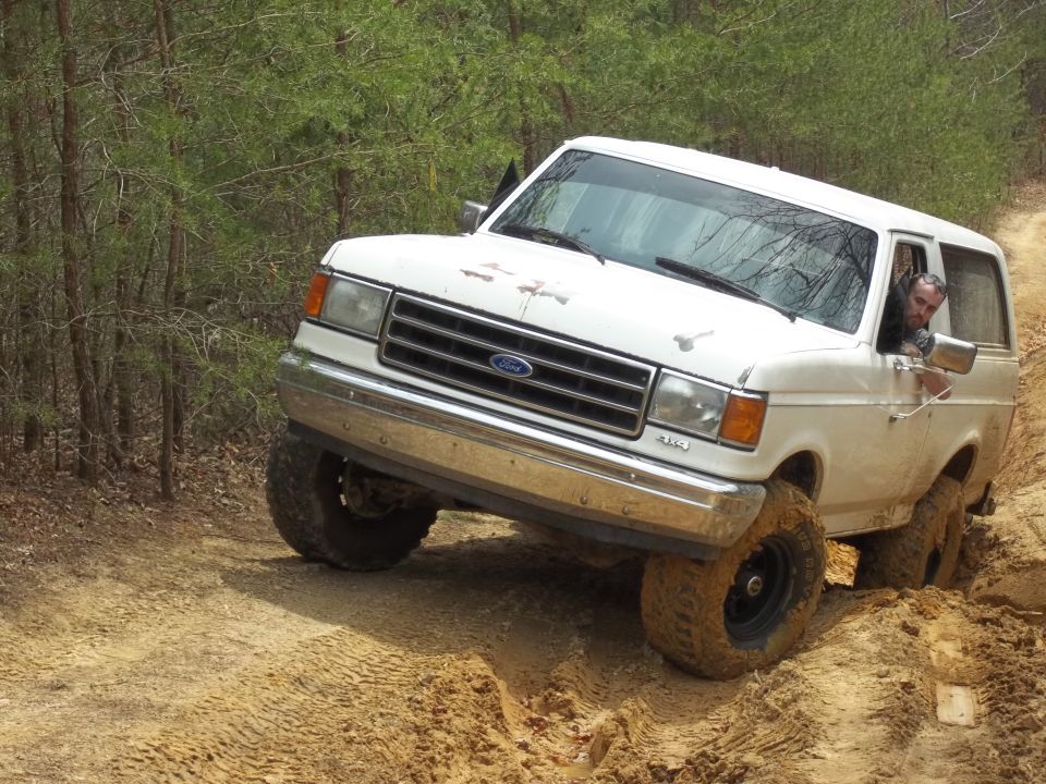White 1990 Ford Bronco navigating a muddy off-road trail