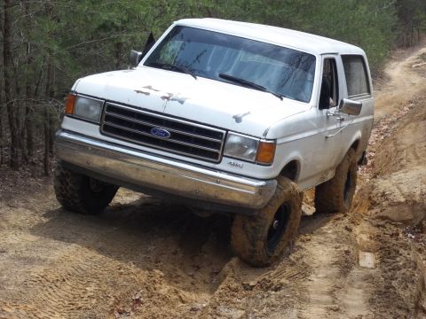 1990 Ford Bronco - White 1990 Ford Bronco tackles an off-road trail with significant articulation.