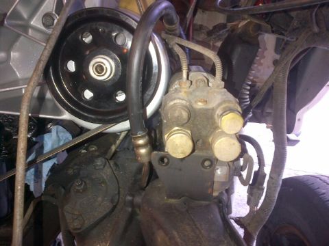 1994 Ford Bronco - Close-up view of engine parts, including a power steering pump and pulley, with visible hoses and wiring.