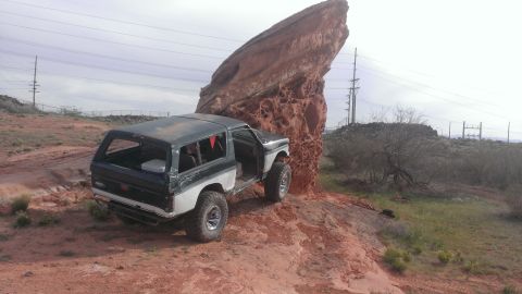 1994 Ford Bronco - This 1994 Ford Bronco navigates a rocky desert terrain, dwarfed by a massive geological formation.