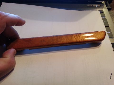 1994 Ford Bronco - A hand holds a wood grain trim piece, possibly for a car interior, over a laptop.