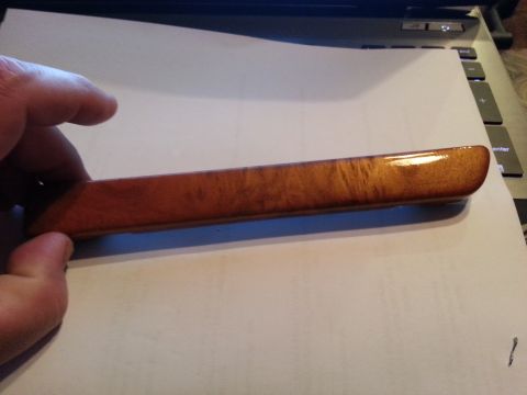 1994 Ford Bronco - A hand holds a piece of wood trim with a burl pattern, likely an interior car part.